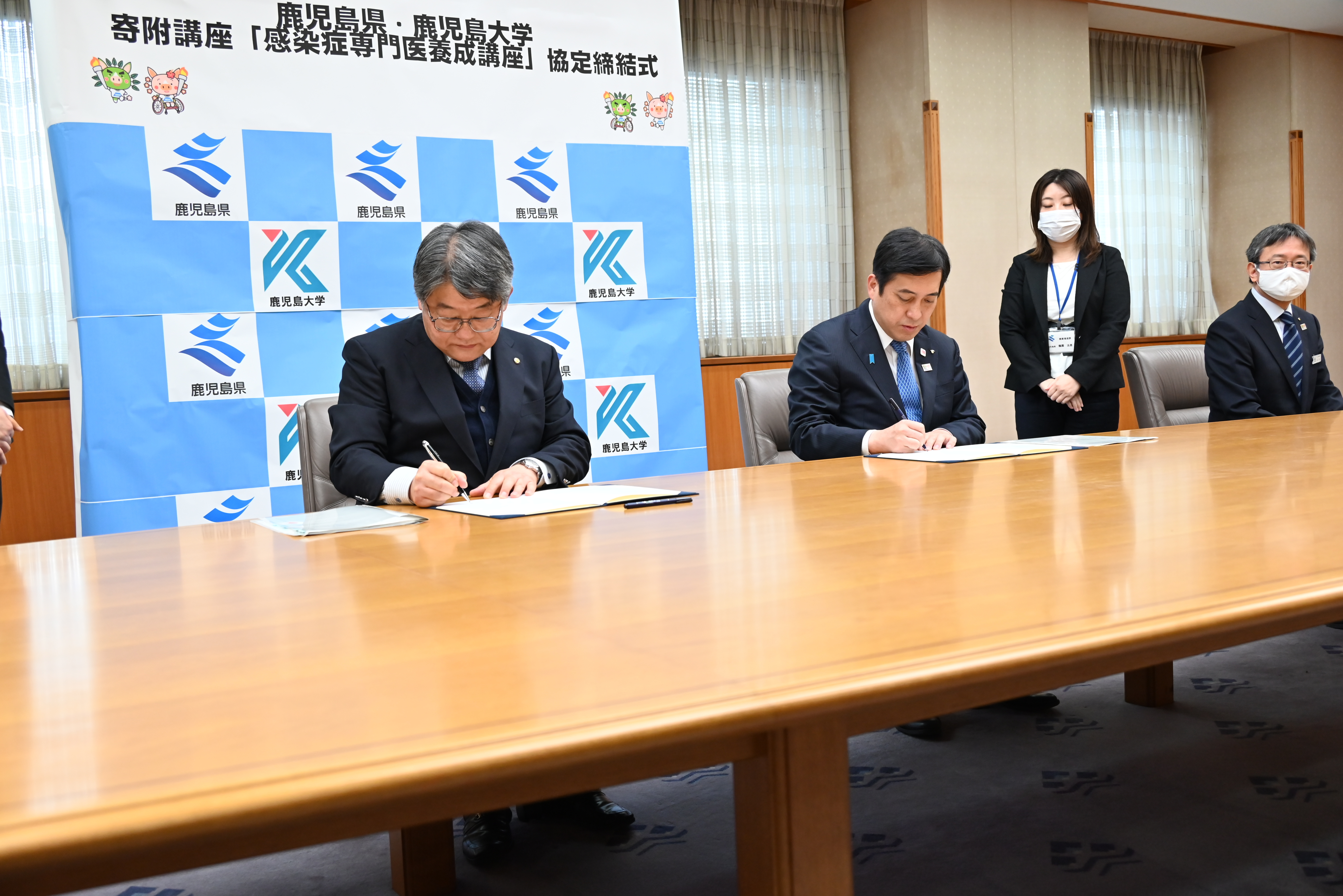 協定書にサインする佐野学長（左）と塩田知事（中央）